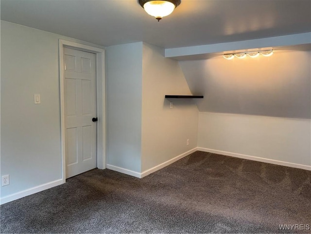 empty room featuring baseboards and dark carpet