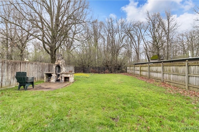 view of yard featuring an outdoor stone fireplace, a fenced backyard, and a patio