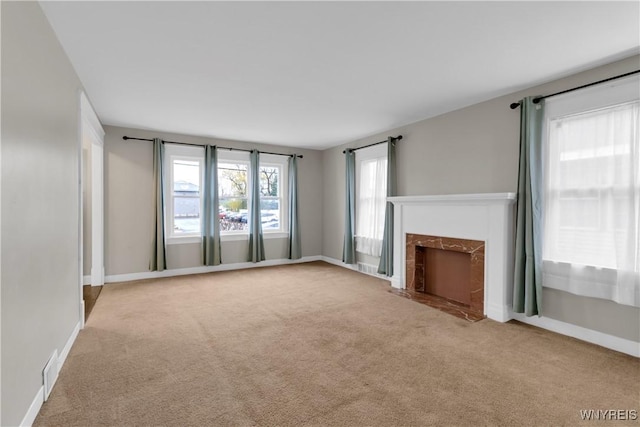 unfurnished living room featuring carpet flooring, baseboards, a fireplace with flush hearth, and visible vents