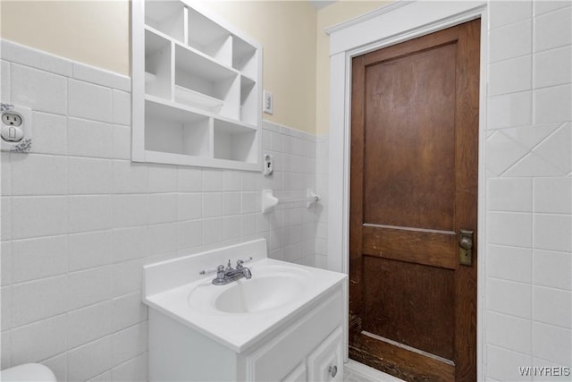 bathroom with vanity, wainscoting, and tile walls