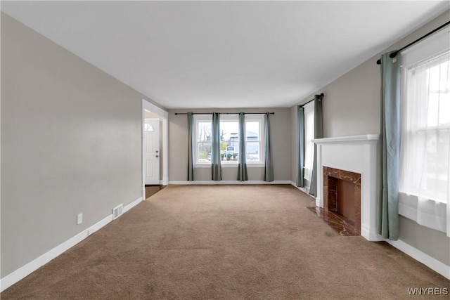 unfurnished living room featuring plenty of natural light, carpet flooring, baseboards, and a fireplace