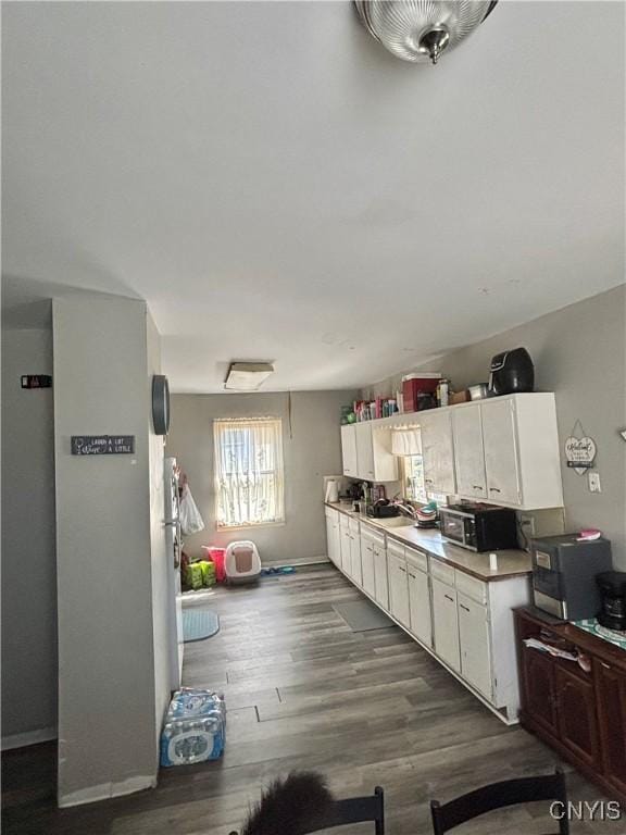 111 N Fulton St, Auburn, NY 13021 - kitchen featuring dark wood-style flooring, a sink, light countertops, white cabinets, and baseboards