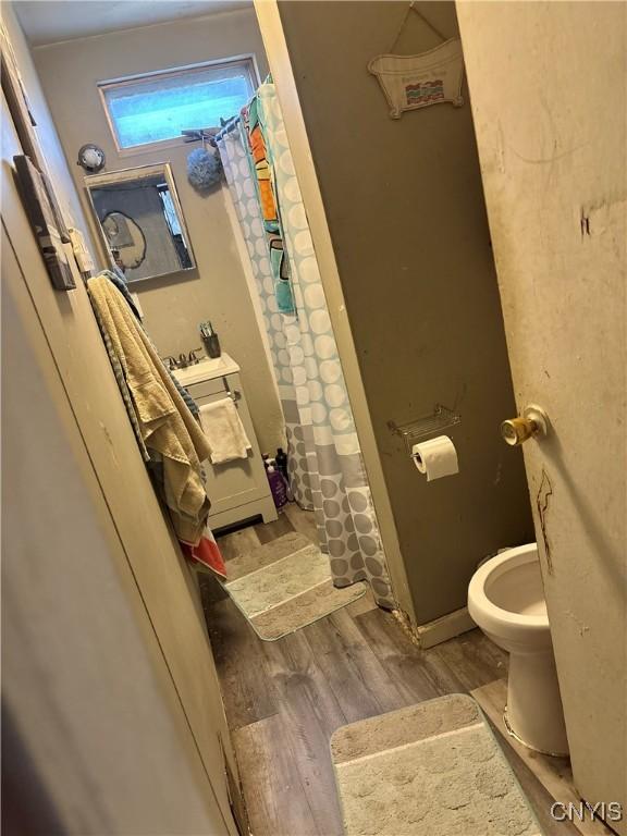 111 N Fulton St, Auburn, NY 13021 - full bathroom featuring curtained shower, toilet, and wood finished floors