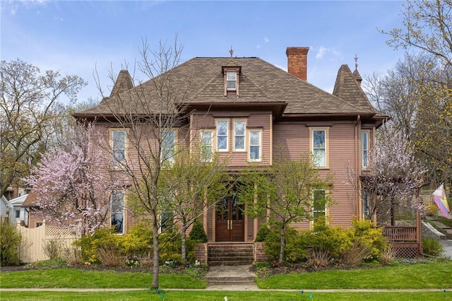 view of front of property featuring a chimney, fence, and a front yard