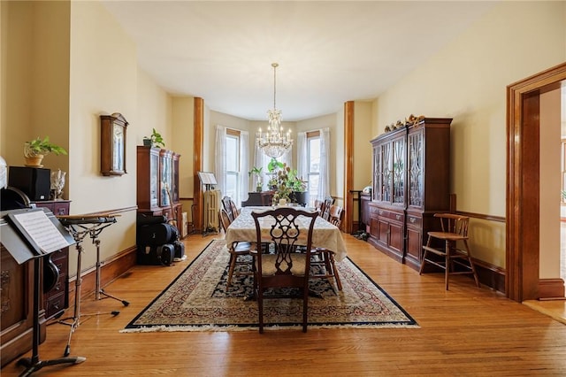dining area with light wood-type flooring and a notable chandelier