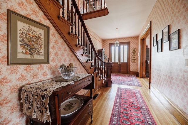 entryway with stairway, wallpapered walls, baseboards, and light wood finished floors