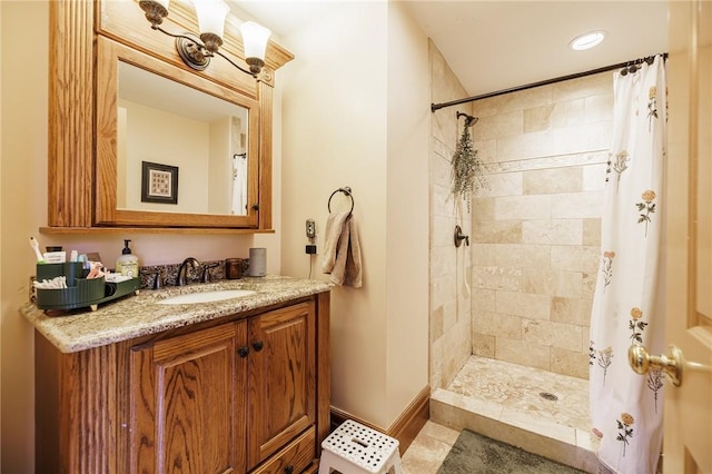 full bath with vanity, baseboards, a tile shower, and recessed lighting