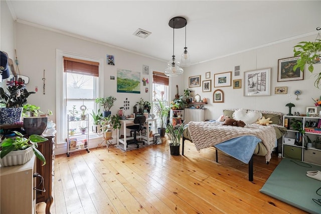 bedroom featuring multiple windows, ornamental molding, and light wood-style flooring