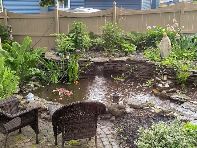 view of yard featuring fence and a garden pond