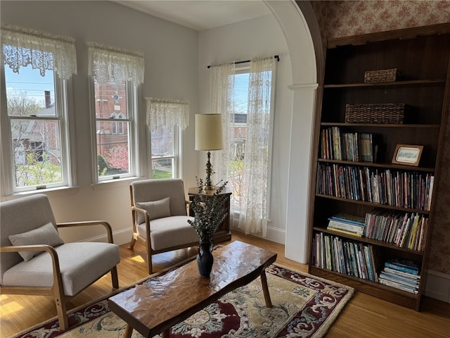 sitting room with baseboards, plenty of natural light, and wood finished floors