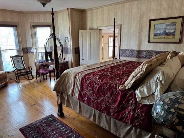 bedroom featuring crown molding, hardwood / wood-style flooring, and wallpapered walls
