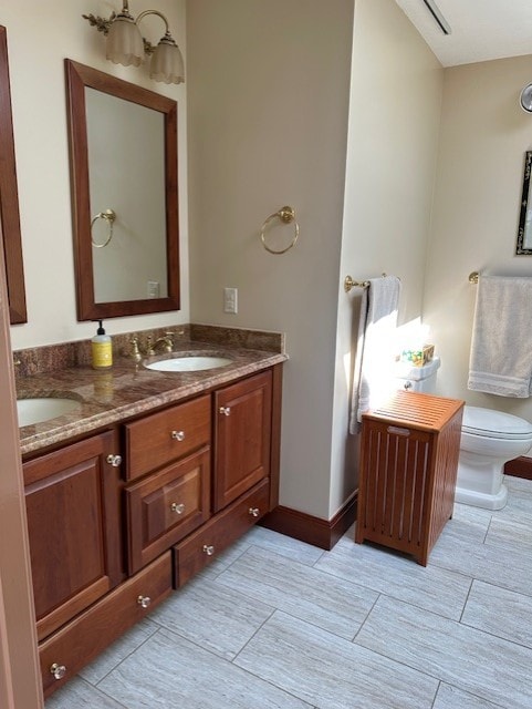 bathroom featuring double vanity, toilet, a sink, and tile patterned flooring
