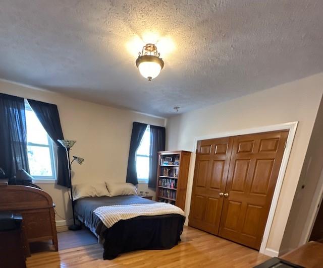 bedroom featuring a closet, light wood finished floors, and a textured ceiling