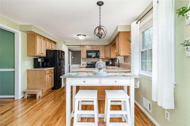 kitchen featuring visible vents, light countertops, tasteful backsplash, light wood finished floors, and black appliances