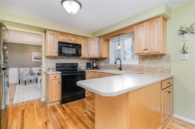 kitchen featuring light brown cabinetry, light wood-style floors, light countertops, a sink, and black appliances