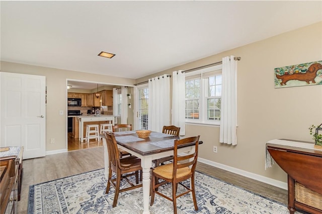 dining space with baseboards and light wood finished floors