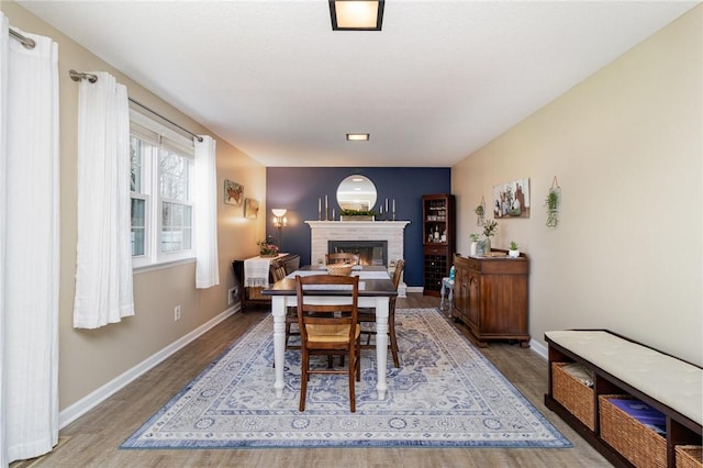 dining area with baseboards, wood finished floors, and a fireplace