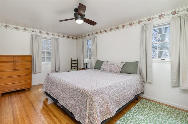 bedroom with baseboards, multiple windows, and wood finished floors