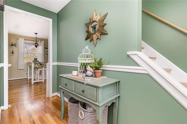 corridor with baseboards, stairs, and wood finished floors