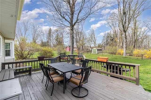 wooden deck with a lawn, outdoor dining space, a fenced backyard, and a shed