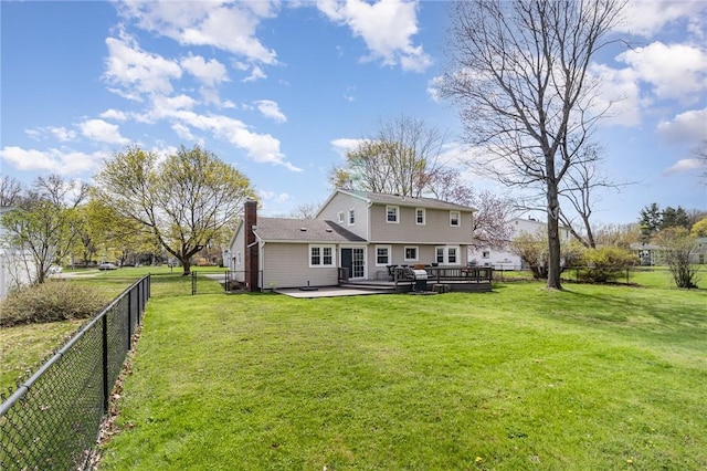 rear view of house with a lawn, a chimney, a fenced backyard, and a wooden deck