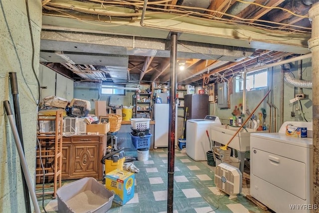 below grade area with tile patterned floors, electric panel, a wealth of natural light, and washing machine and dryer
