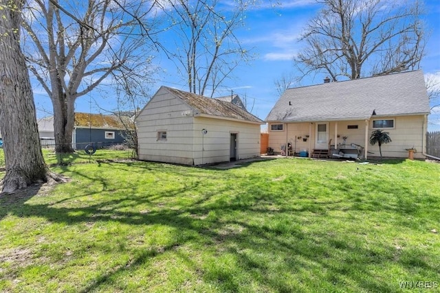 rear view of house featuring an outdoor structure, fence, and a yard