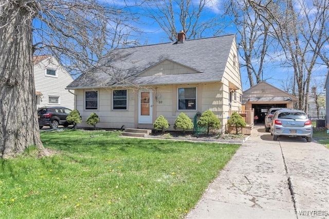 view of front of house with roof with shingles, a front lawn, a detached garage, a chimney, and an outdoor structure