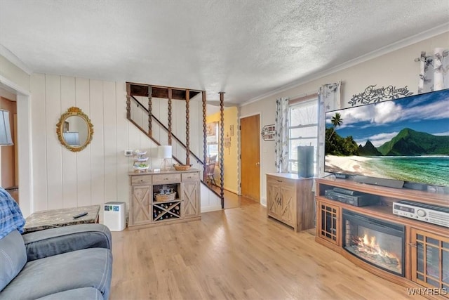 living area with crown molding, a textured ceiling, stairway, and wood finished floors