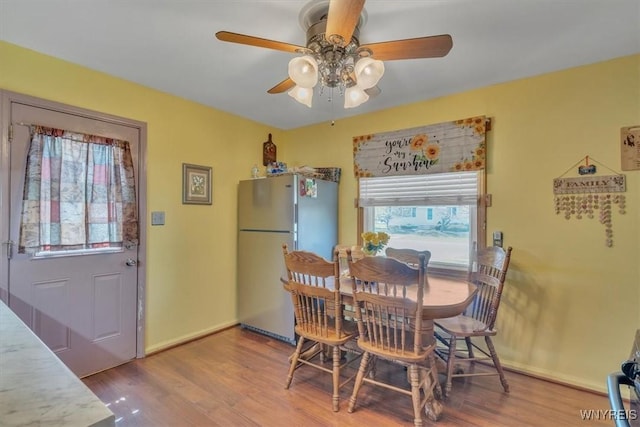 dining space with baseboards, a ceiling fan, and wood finished floors