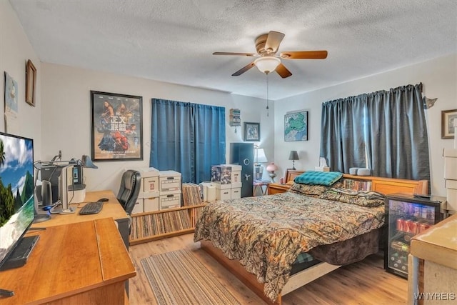 bedroom with light wood-style floors, ceiling fan, and a textured ceiling