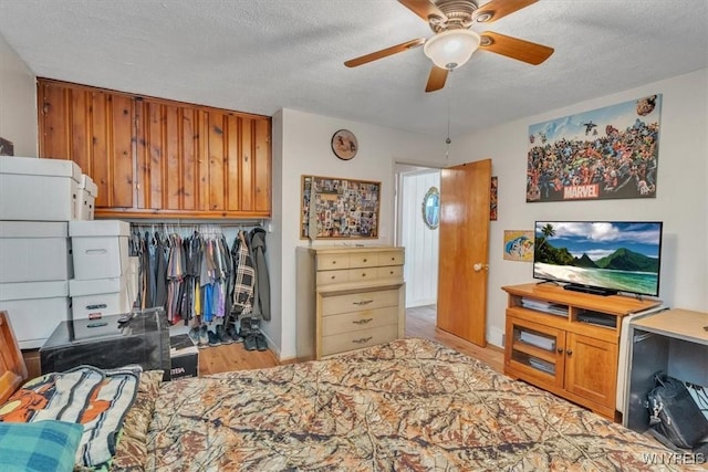 bedroom with a closet, a ceiling fan, a textured ceiling, and wood finished floors