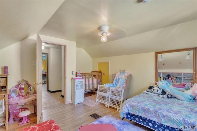 bedroom featuring vaulted ceiling, visible vents, and light wood-style floors
