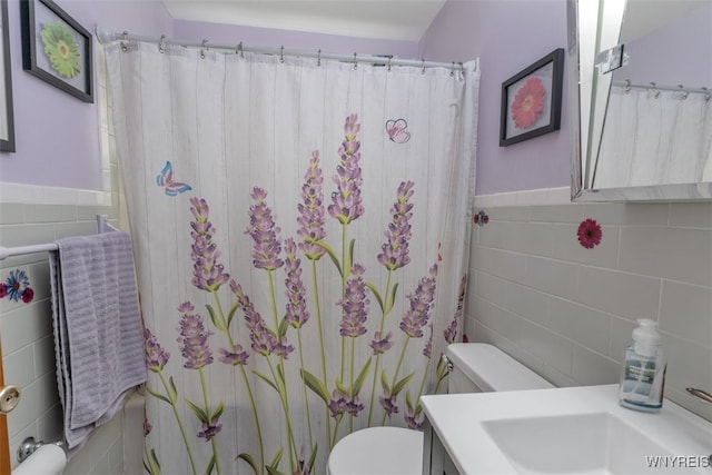 full bathroom with tile walls, a wainscoted wall, vanity, and toilet