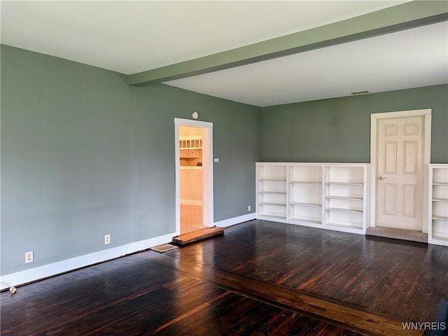 empty room with baseboards, beamed ceiling, hardwood / wood-style flooring, and visible vents