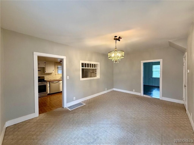 spare room featuring dark carpet, baseboards, a notable chandelier, and visible vents
