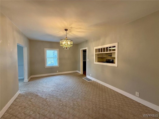 spare room with carpet floors, visible vents, baseboards, and a notable chandelier