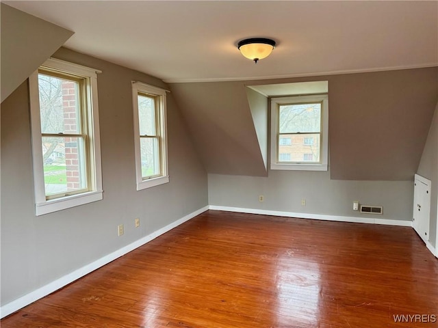additional living space featuring visible vents, baseboards, lofted ceiling, and wood finished floors