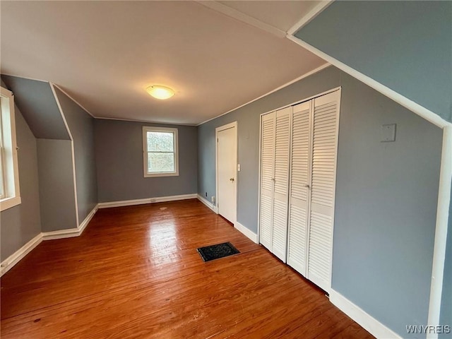 additional living space featuring baseboards, wood finished floors, and visible vents