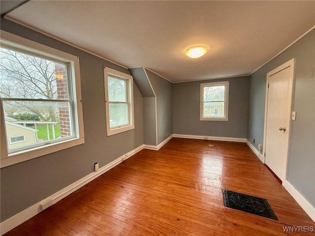 additional living space featuring baseboards, visible vents, and wood finished floors