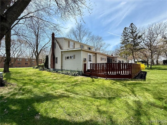 rear view of house featuring a chimney, a yard, and a deck