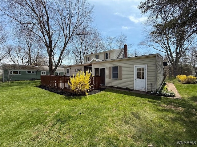 back of house with a yard, a deck, and a chimney