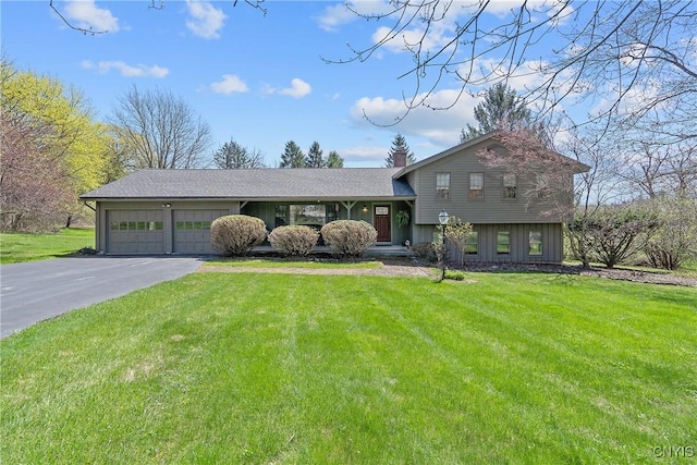 split level home featuring an attached garage, a front yard, and aphalt driveway