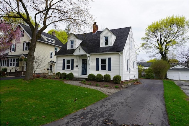 new england style home with roof with shingles, a front yard, a chimney, and entry steps