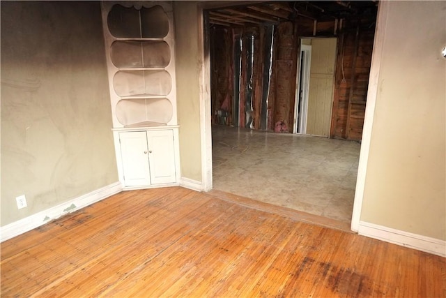 spare room featuring baseboards and wood finished floors