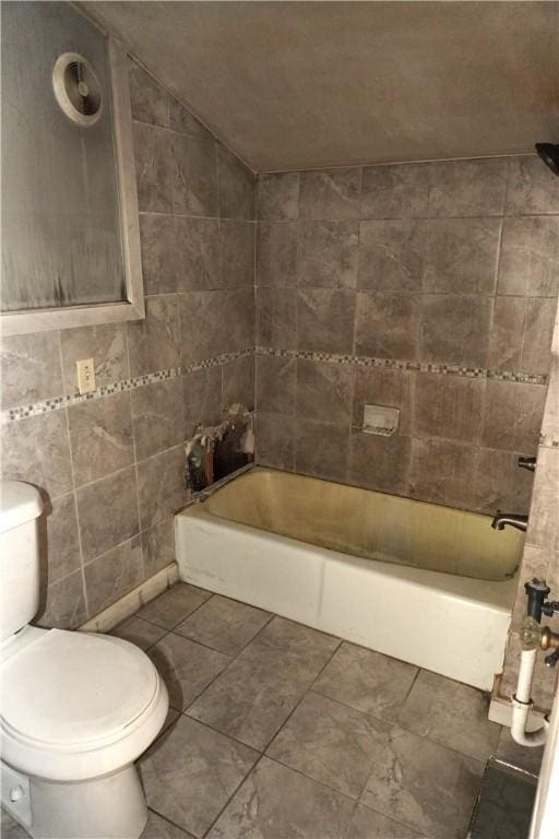 full bathroom featuring tile patterned flooring, toilet, tile walls, bathing tub / shower combination, and vaulted ceiling