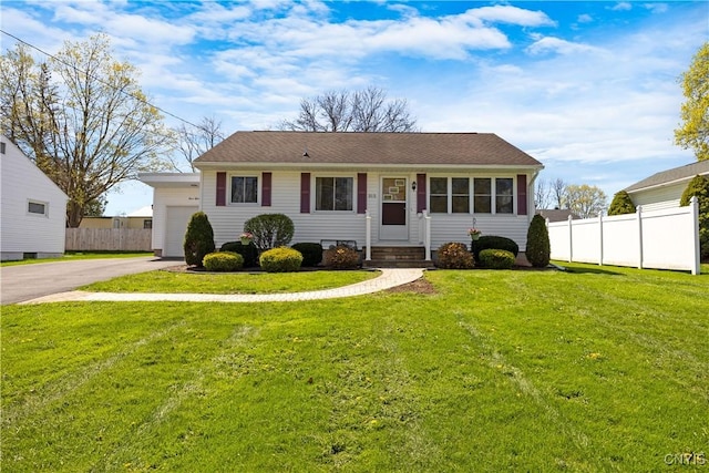 view of front facade with fence, entry steps, a front lawn, and aphalt driveway
