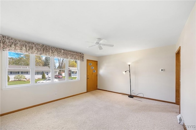 empty room with baseboards, light carpet, a ceiling fan, and a wealth of natural light