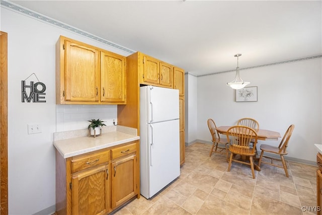 kitchen with light countertops, freestanding refrigerator, decorative light fixtures, baseboards, and decorative backsplash