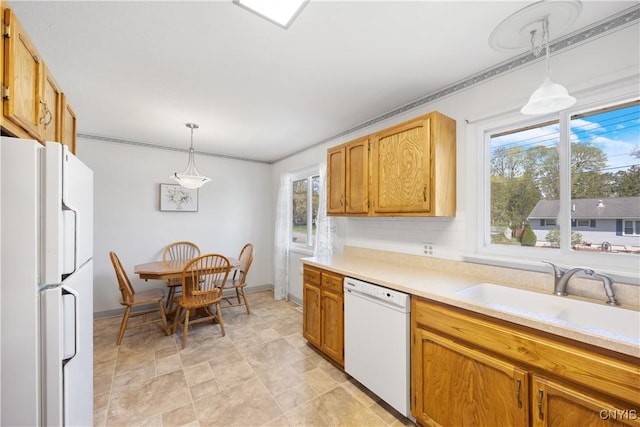 kitchen featuring a sink, decorative light fixtures, white appliances, and light countertops
